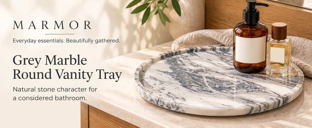 Marmor grey marble round vanity tray holding a soap dispenser and perfume bottle on a bathroom countertop.