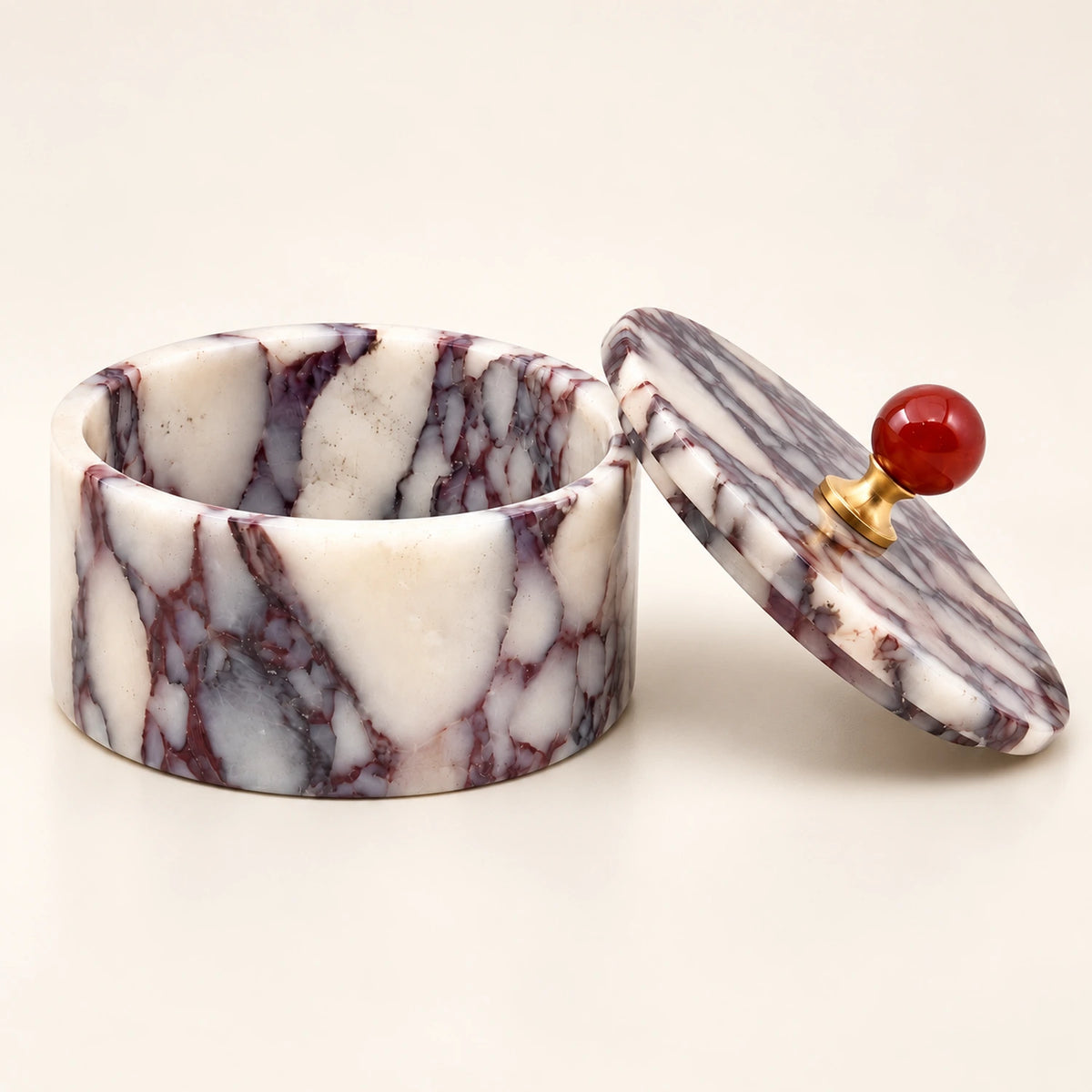 Round purple and white marble jewelry box with an empty interior and a removable lid featuring a red knob and gold-tone base.