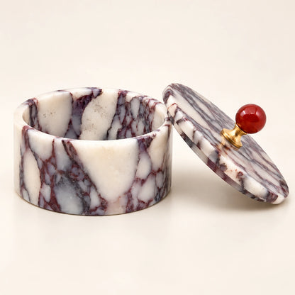 Round purple and white marble jewelry box with an empty interior and a removable lid featuring a red knob and gold-tone base.