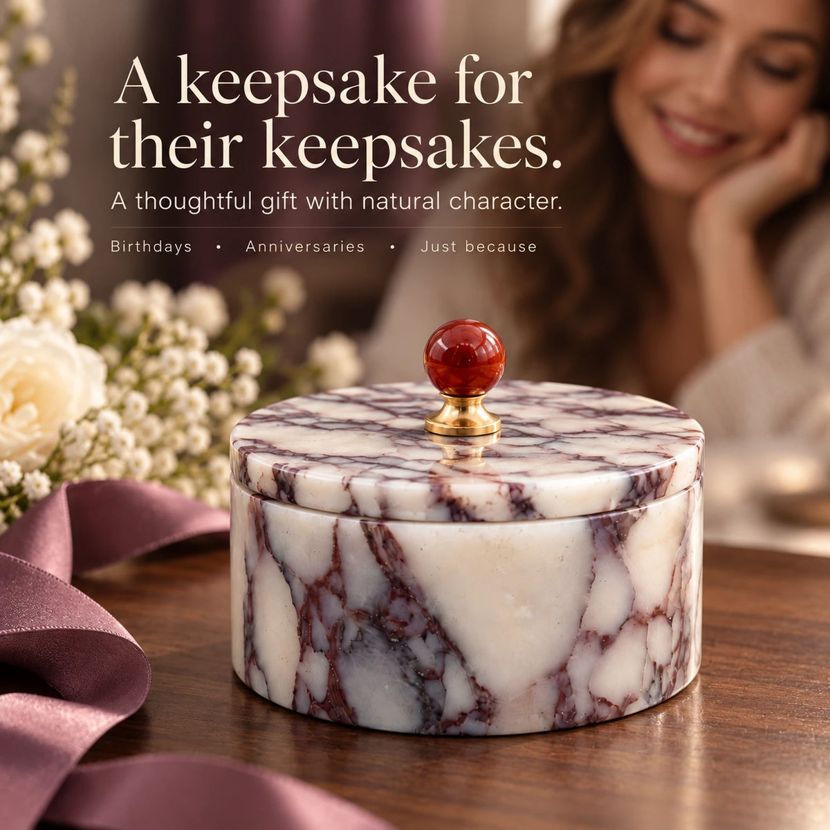 Purple marble jewelry box with a red lid knob displayed beside flowers and ribbon as a birthday or anniversary gift.