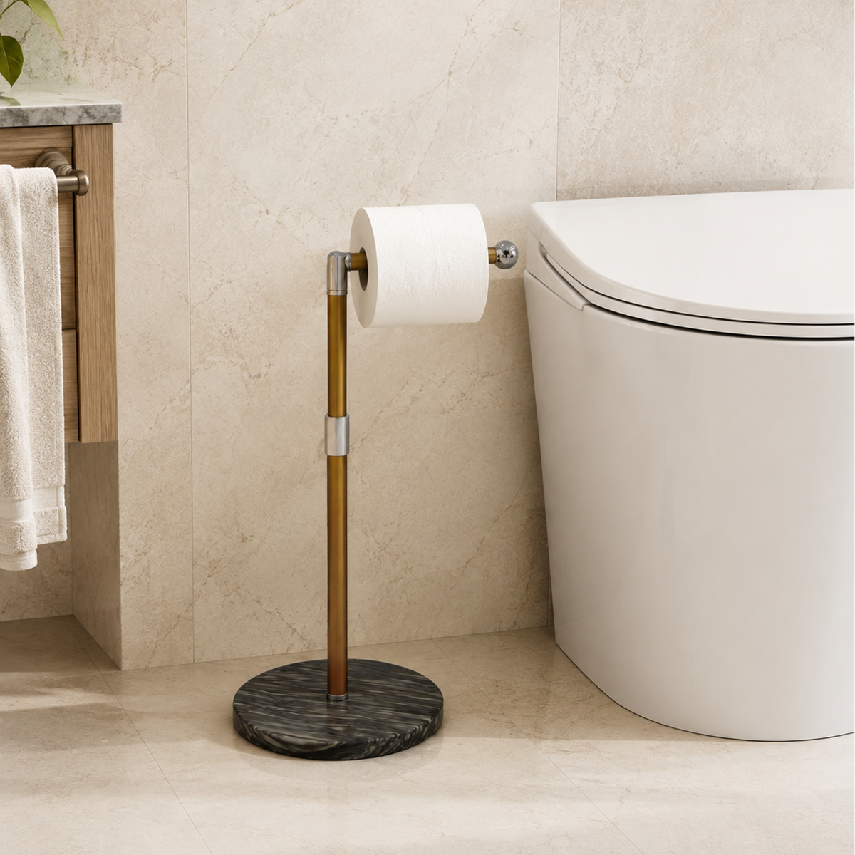 A toilet paper holder with a brushed brass stand and a round black marble base, holding a roll of white toilet paper in a modern bathroom setting next to a white toilet.