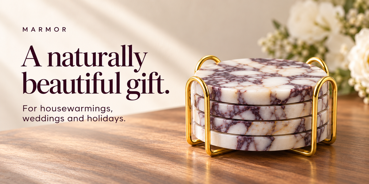 Four purple marble coasters stacked in a gold-tone metal holder beside white flowers.