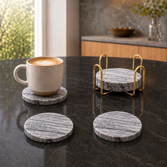 Light grey wood grain marble drink coasters set with gold holder on dark kitchen countertop with coffee cup