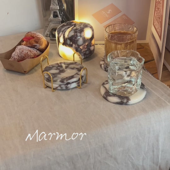 Marmor Calacatta Viola purple marble touch lamp glowing on a linen-covered table with matching marble coasters